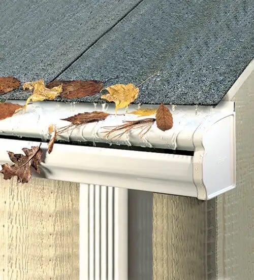 LeafGuard hood-style gutter guard on a white gutter, with leaves sliding off the shingle roof edge