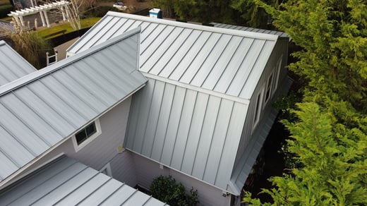 Light gray standing seam metal roof running across several roof planes with different slopes