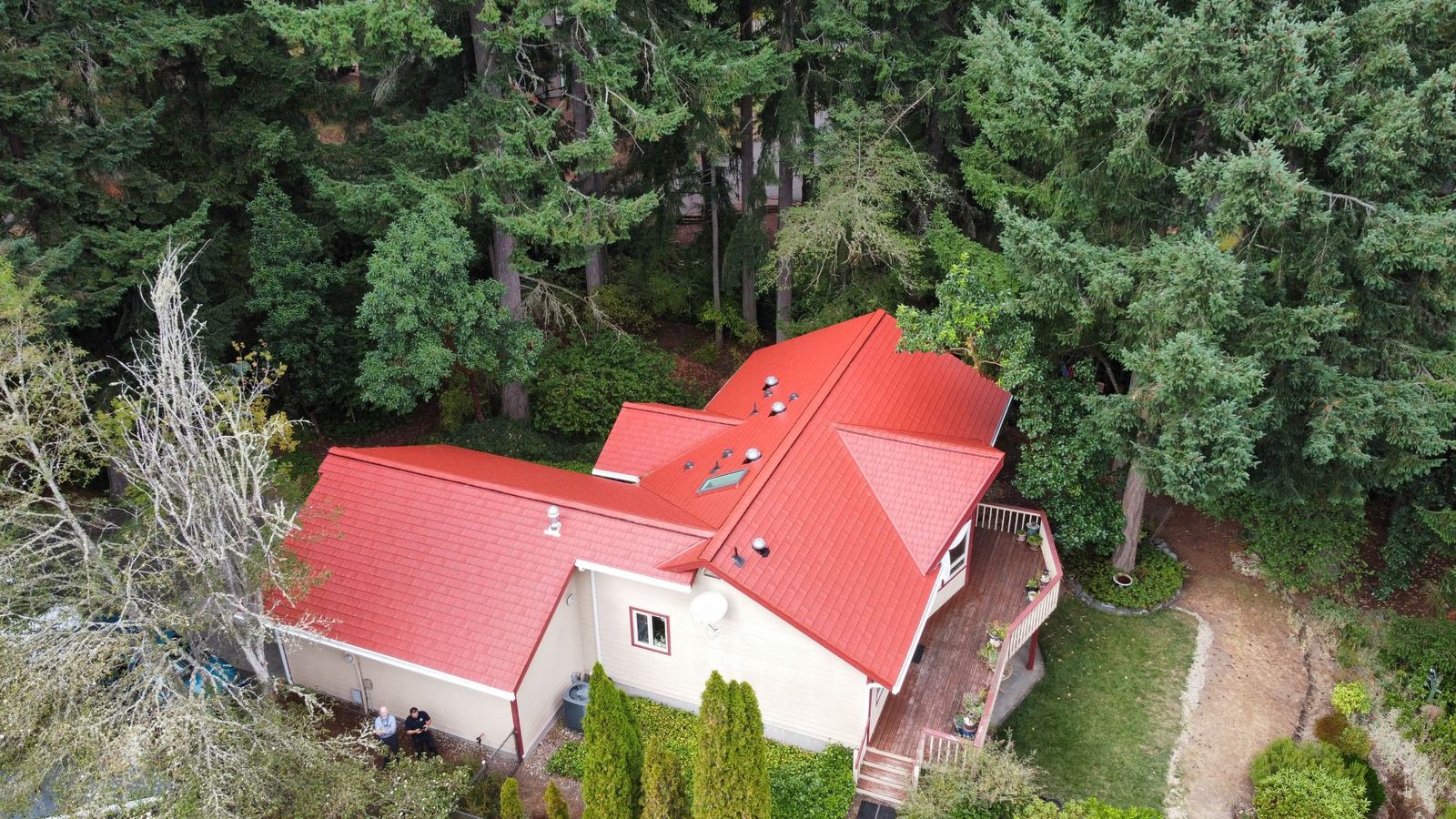 Red stamped metal shingle roof on a wooded lot in Olympia