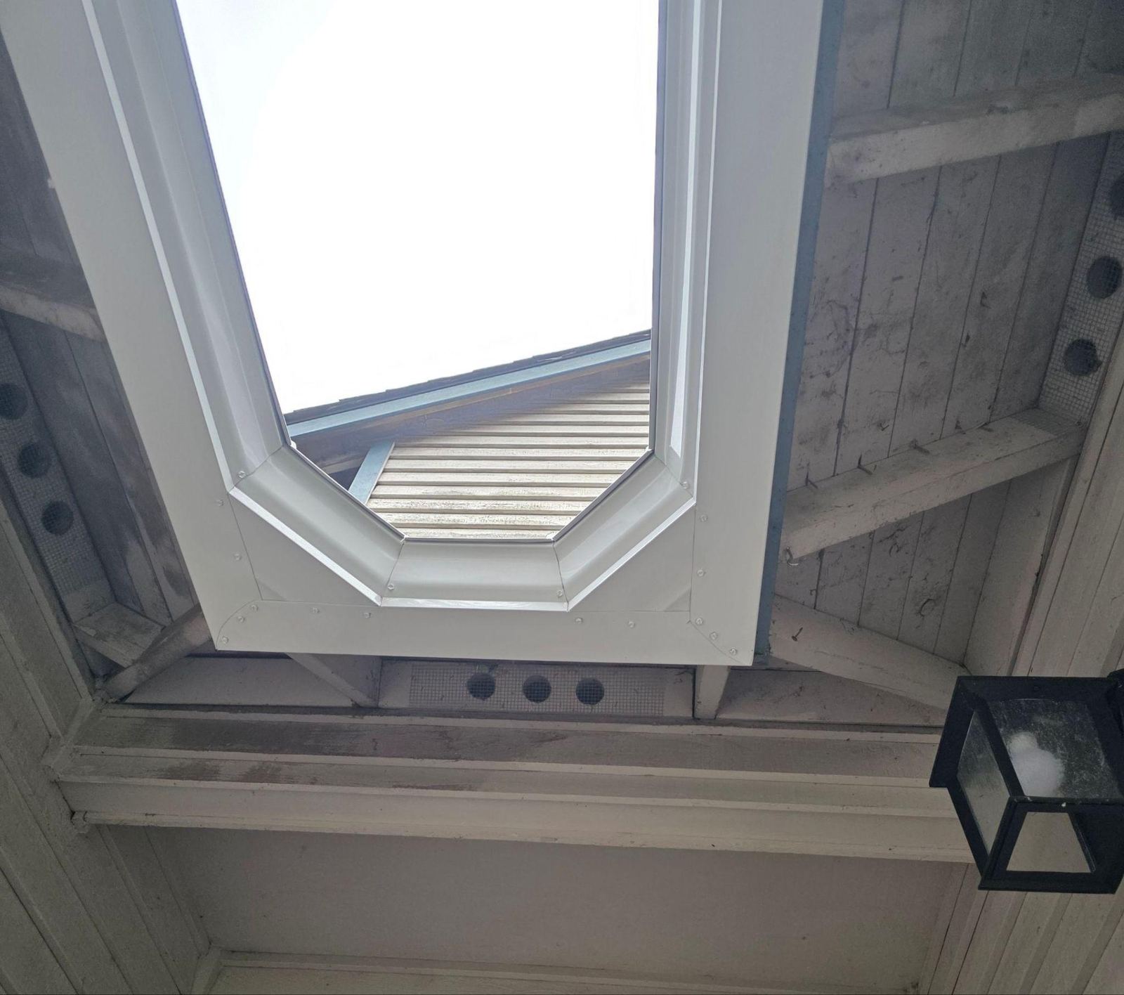View from below of the new white gutters following the angled corners of the roof over the entry