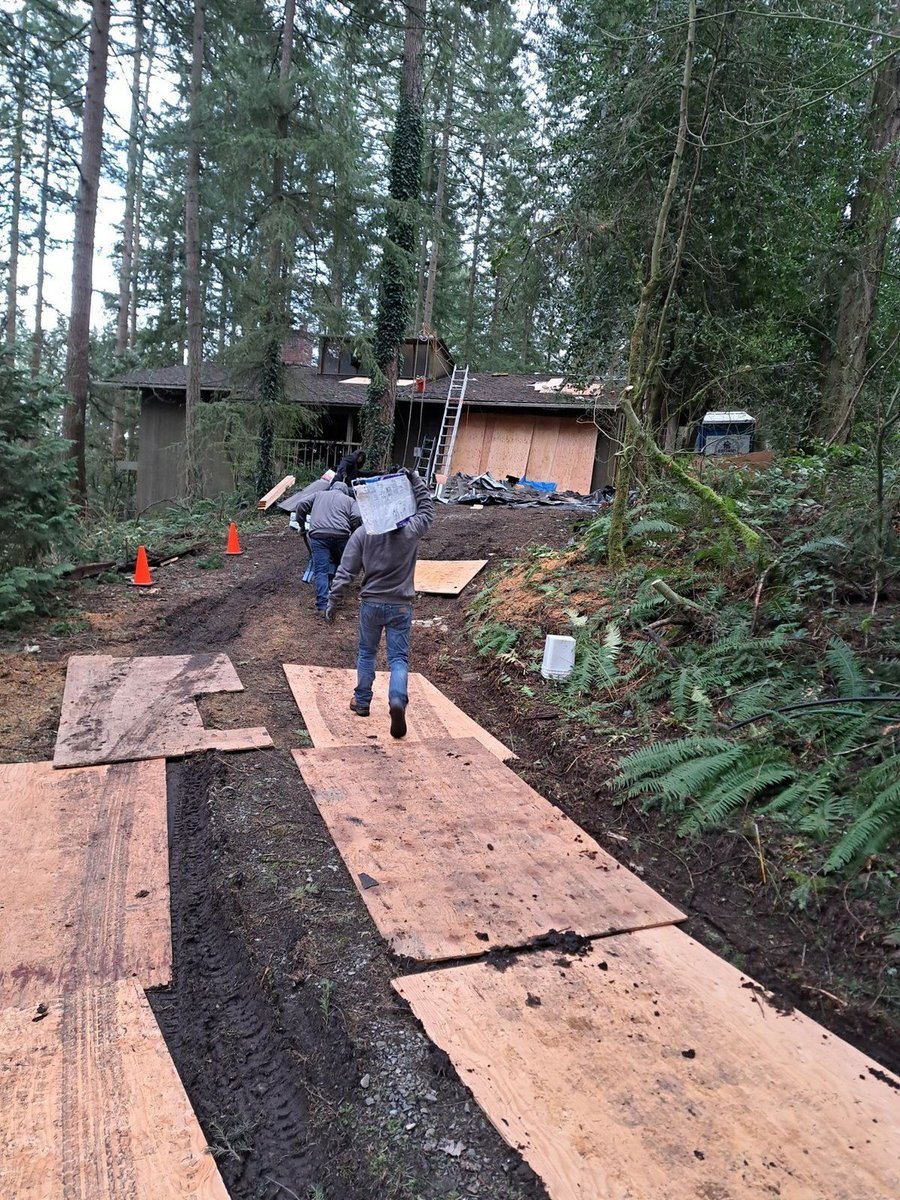 Bellevue: crew carrying roofing materials up a plywood path where a truck cannot get close.