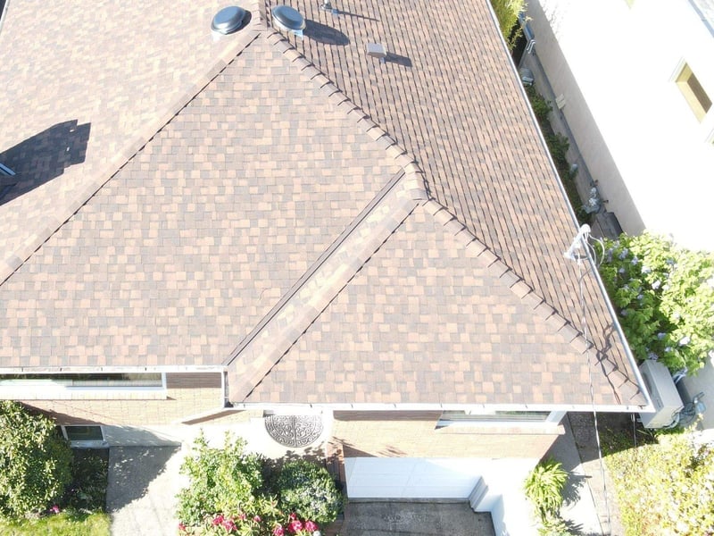 Seattle: finished brown architectural shingles on a hip and valley roof with ridge vents, from a drone.
